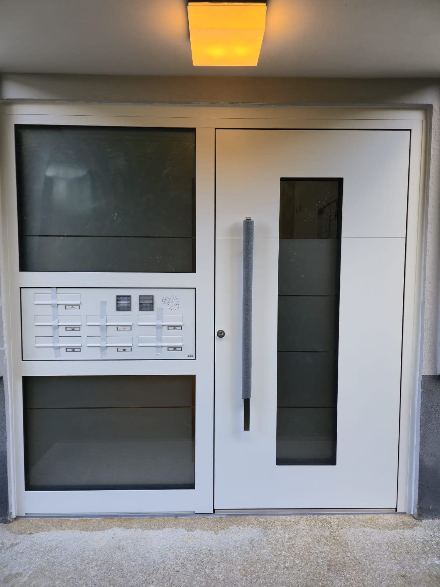 Eingebaute Hauseingangstür in Weiß mit Seitenteil und integrierter Briefkastenanlage