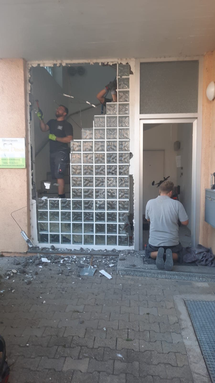 Zwei Monteure von RÜBO öffnen eine alte Glasbausteinwand für einen neuen Hauseingang