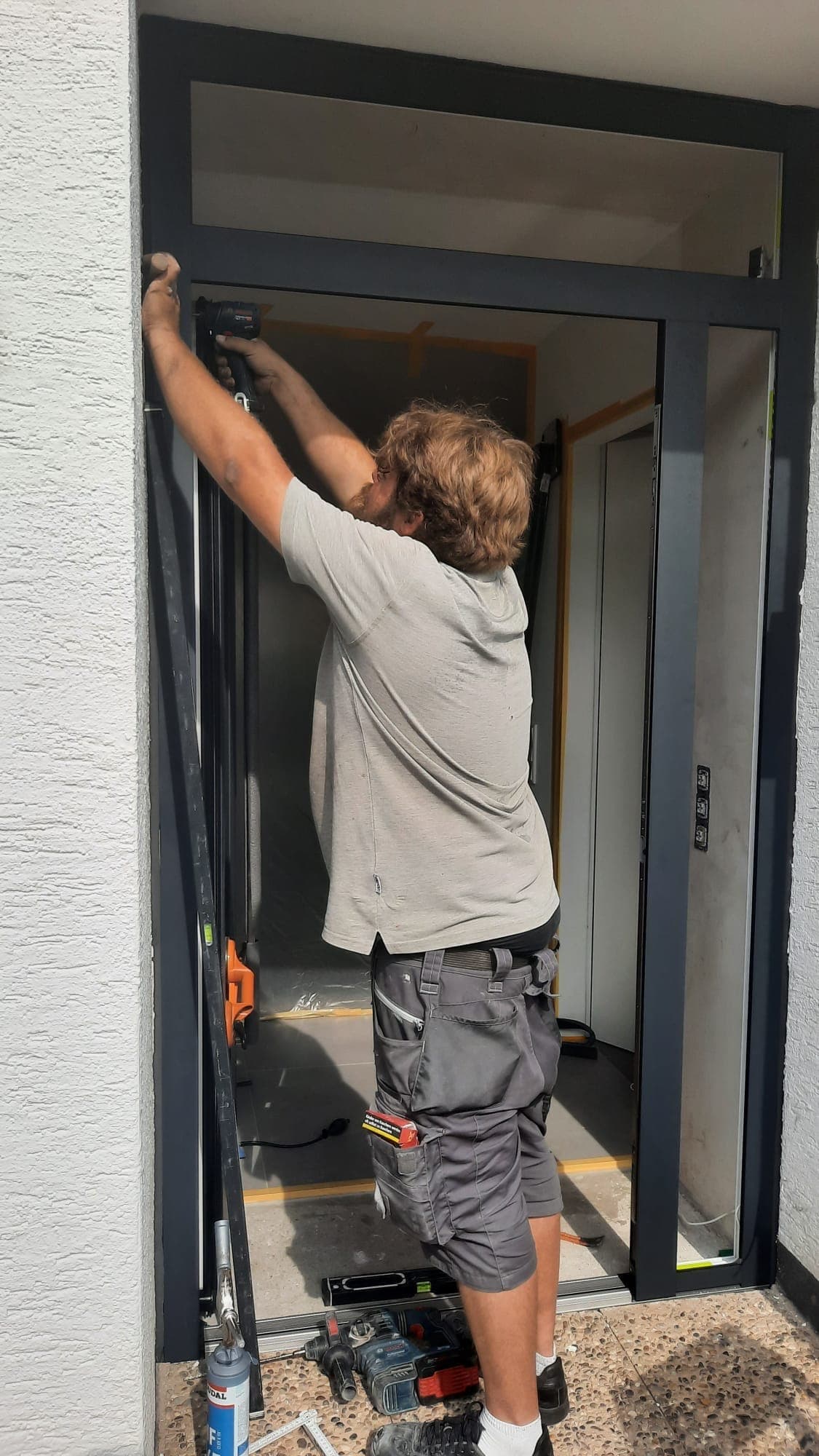 Monteur von RÜBO Fenstersysteme richtet den Rahmen einer neuen Haustür aus