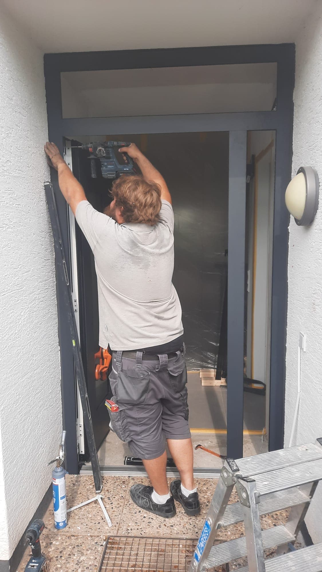 Monteur von RÜBO arbeitet am oberen Rahmenanschluss einer neuen Haustür